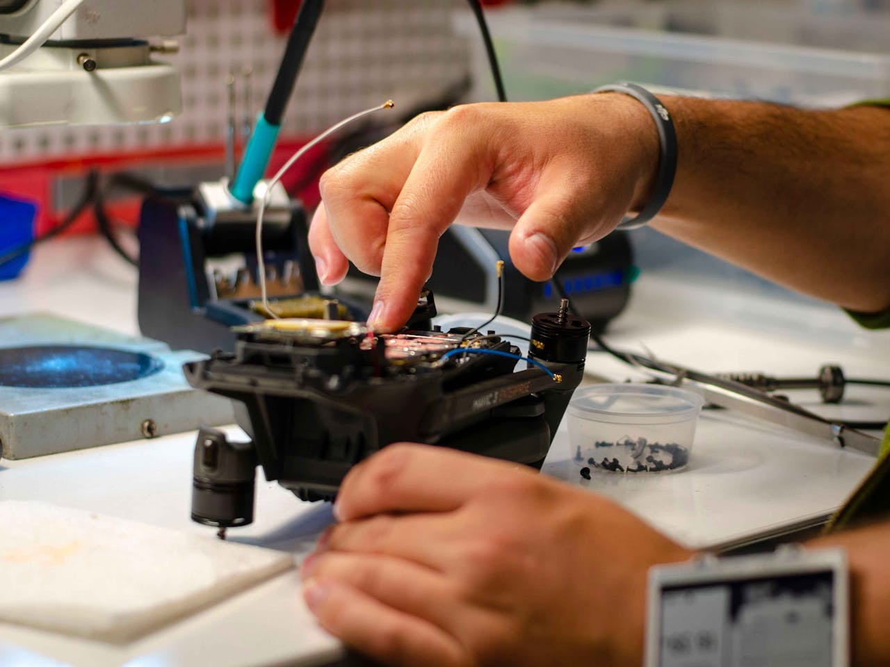 trusted-partner Hands of a technician performing drone repair on a workbench indoors.