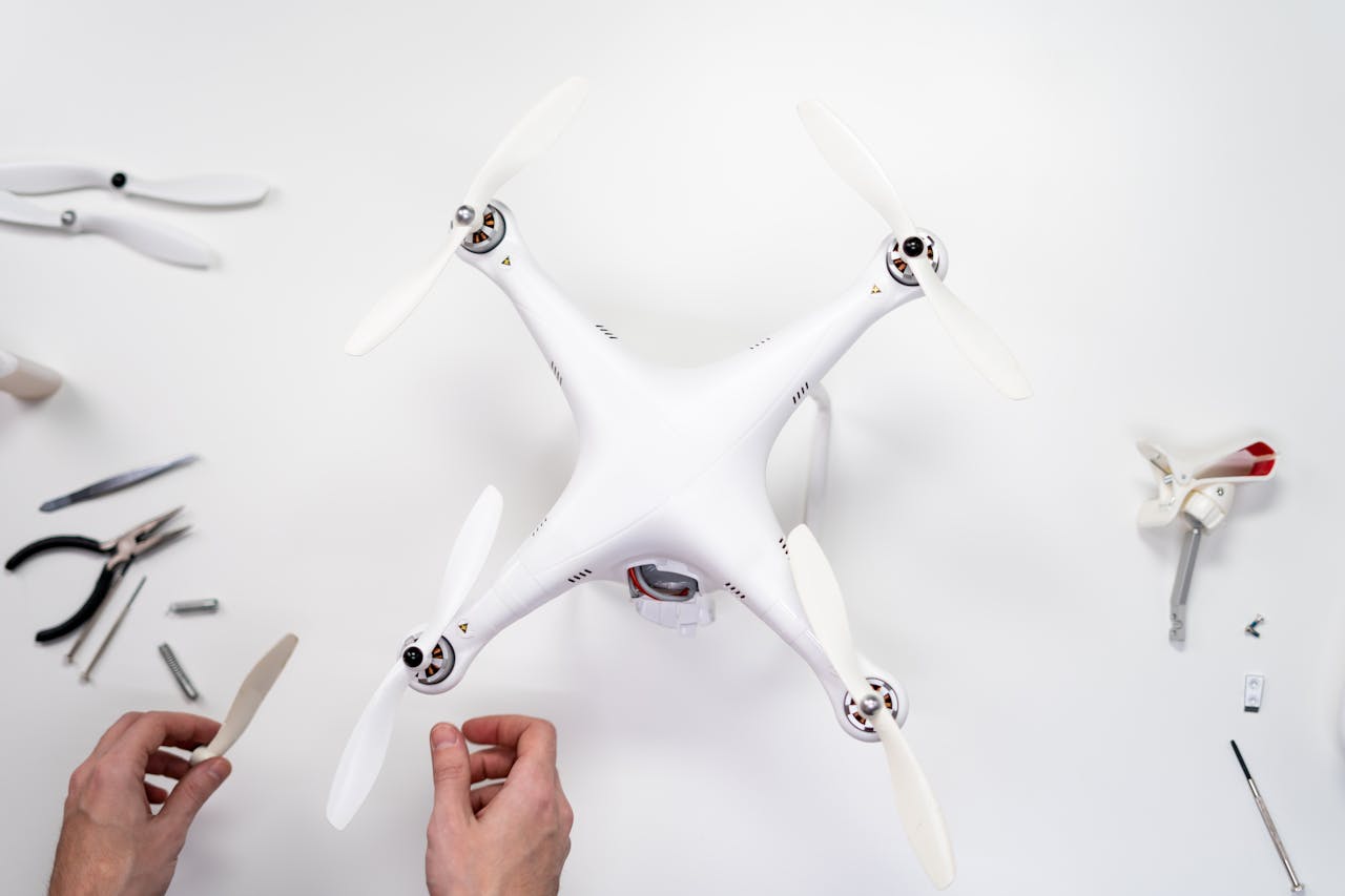vision Hands assembling a quadcopter drone on a white surface with various tools around.