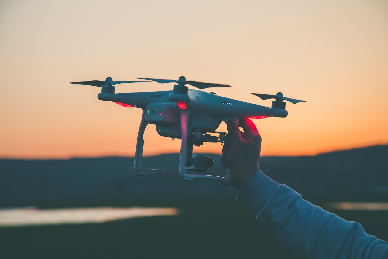 home-img Silhouette of a drone and hand against a colorful sunset backdrop.